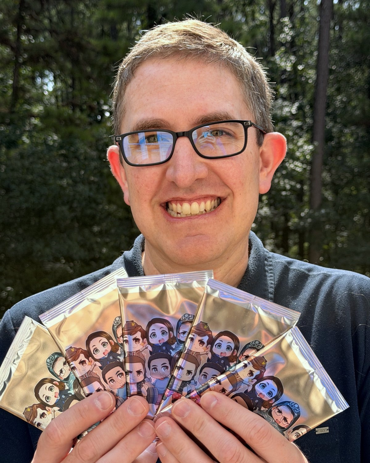 The founder fanning a hand of sealed Deck of Us foil card packs.